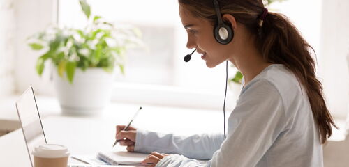 Mitarbeiterin mit Headset im Büro am Computer.